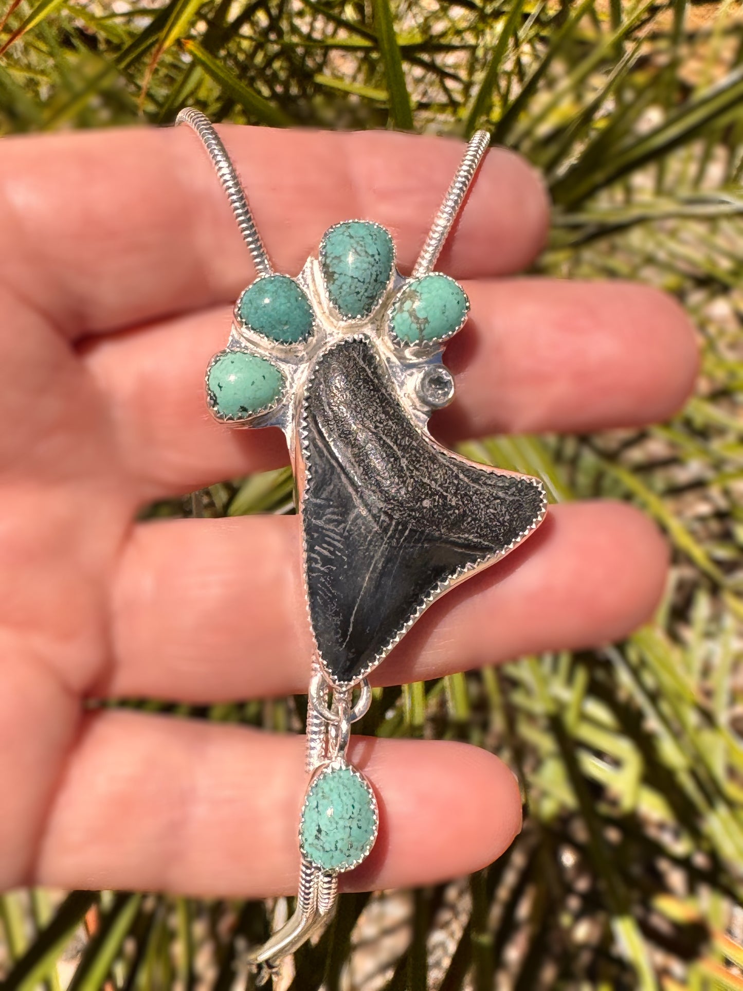 Sterling silver statement, Bolo Necklace with a megalodon fossil tooth and green turquoise in front of a palm tree