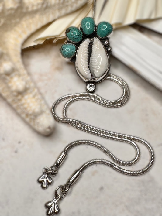 Handmade bolo necklace featuring cowrie shell, Fox turquoise, and white topaz in sterling silver, called Tidebearer.