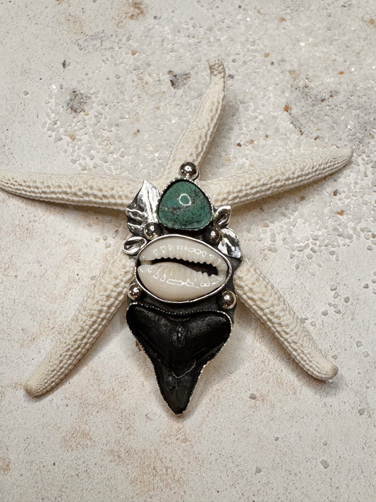 Close-up of a unique silver ring with shark tooth, cowrie shell and green turquoise stones.