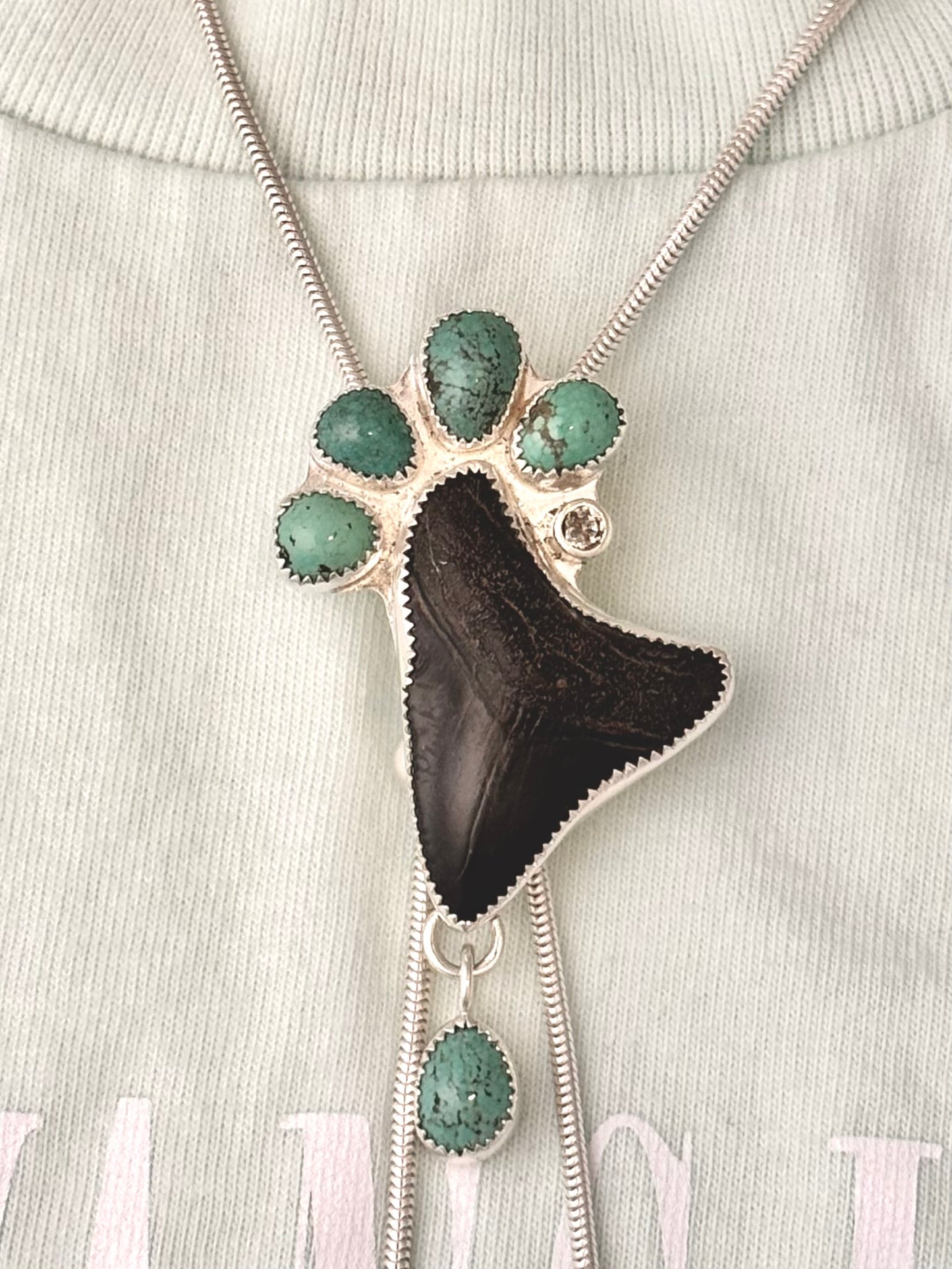 Sterling silver statement, Bolo Necklace with a megalodon fossil tooth, white sapphire and green turquoise on a t-shirt
