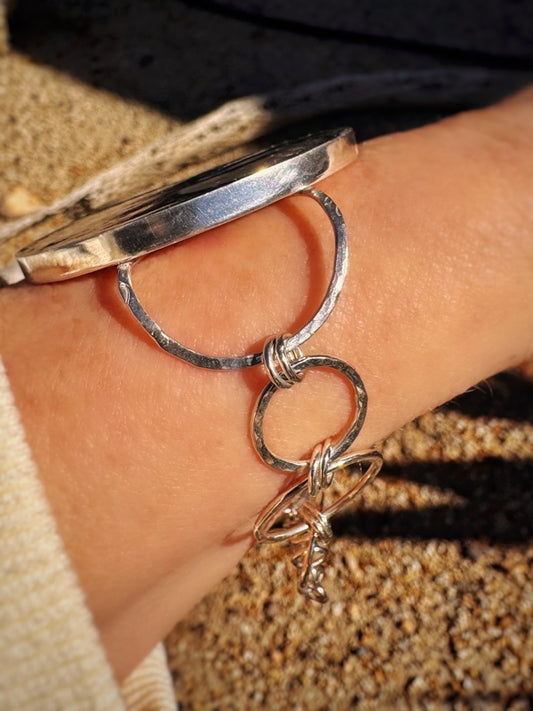 Silver bracelet with a handmade hammered chain on a wrist against a blurred background