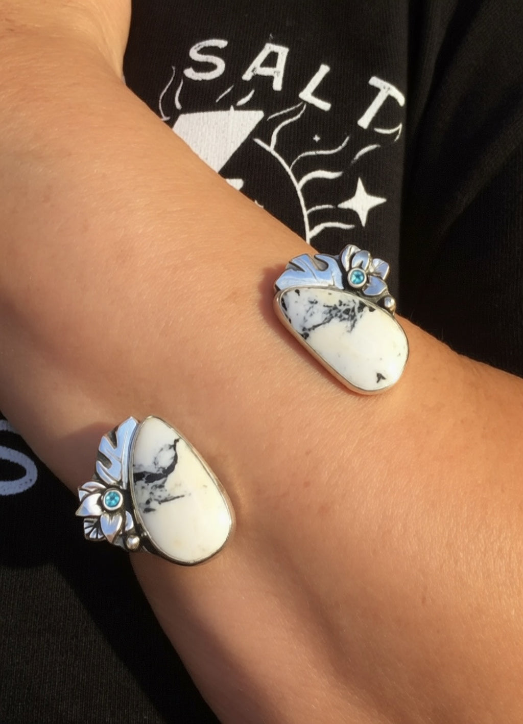 Close-up of a wrist wearing a silver, white buffalo, Montana sapphire and monstera leaf cuff. 
