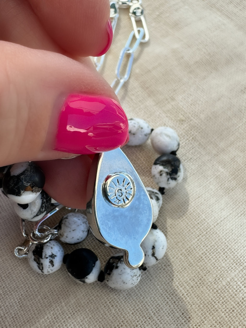 Reverse of the Blue Meridian silver pendant held between fingers, showing the maker’s mark.