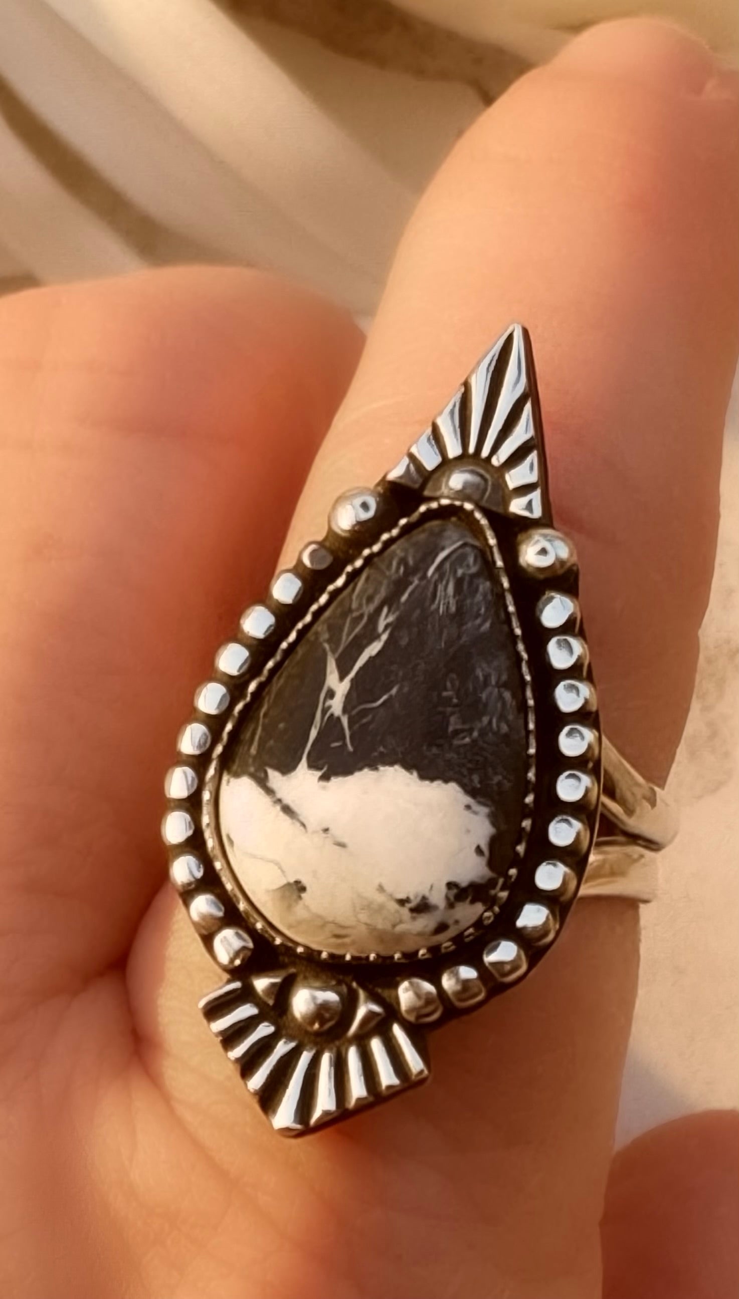 Silver ring with a teardrop-shaped white buffalo stone on a finger