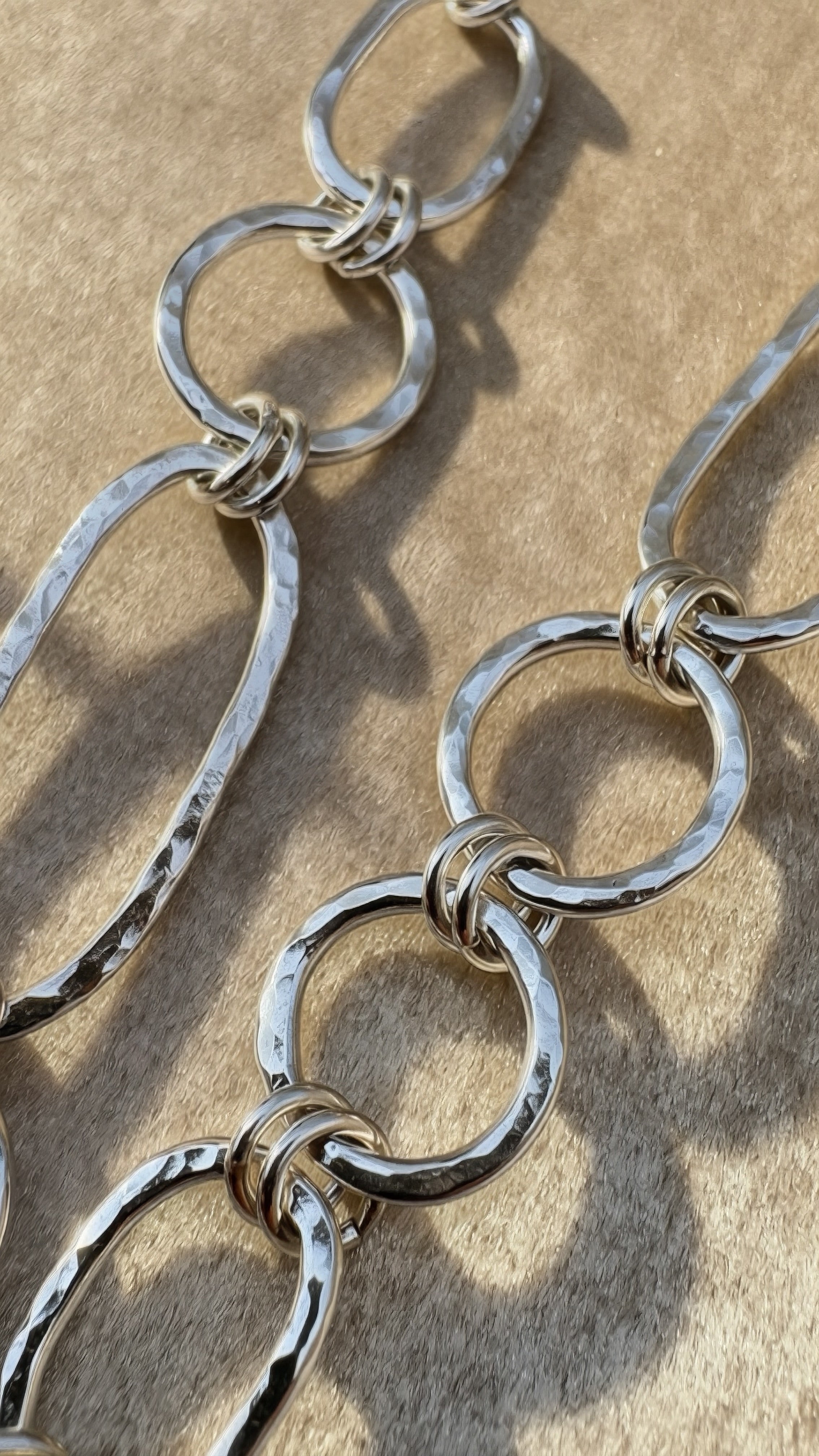 Close-up of a silver chain on a textured beige surface