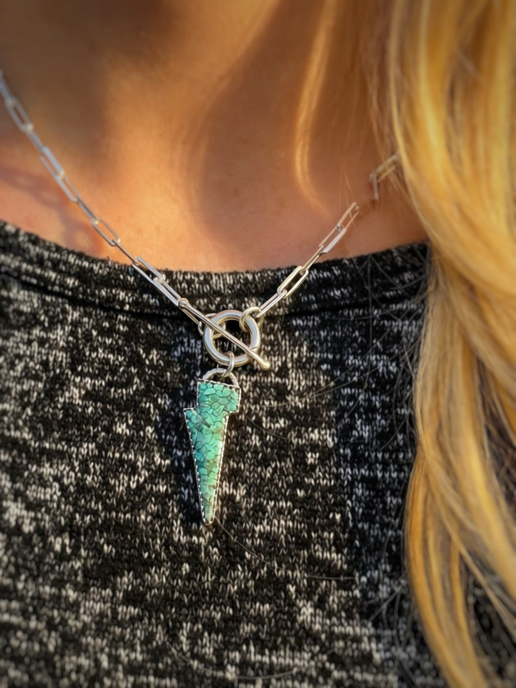 Green Lightning bolt pendant, on a silver paperclip toggle chain, being worn.