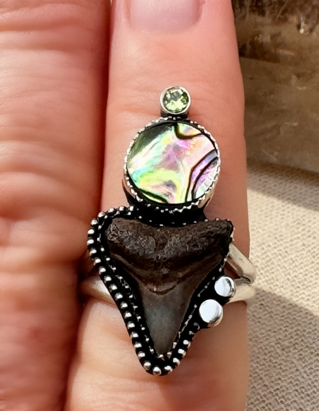 Shark tooth, abalone and peridot ring being worn.