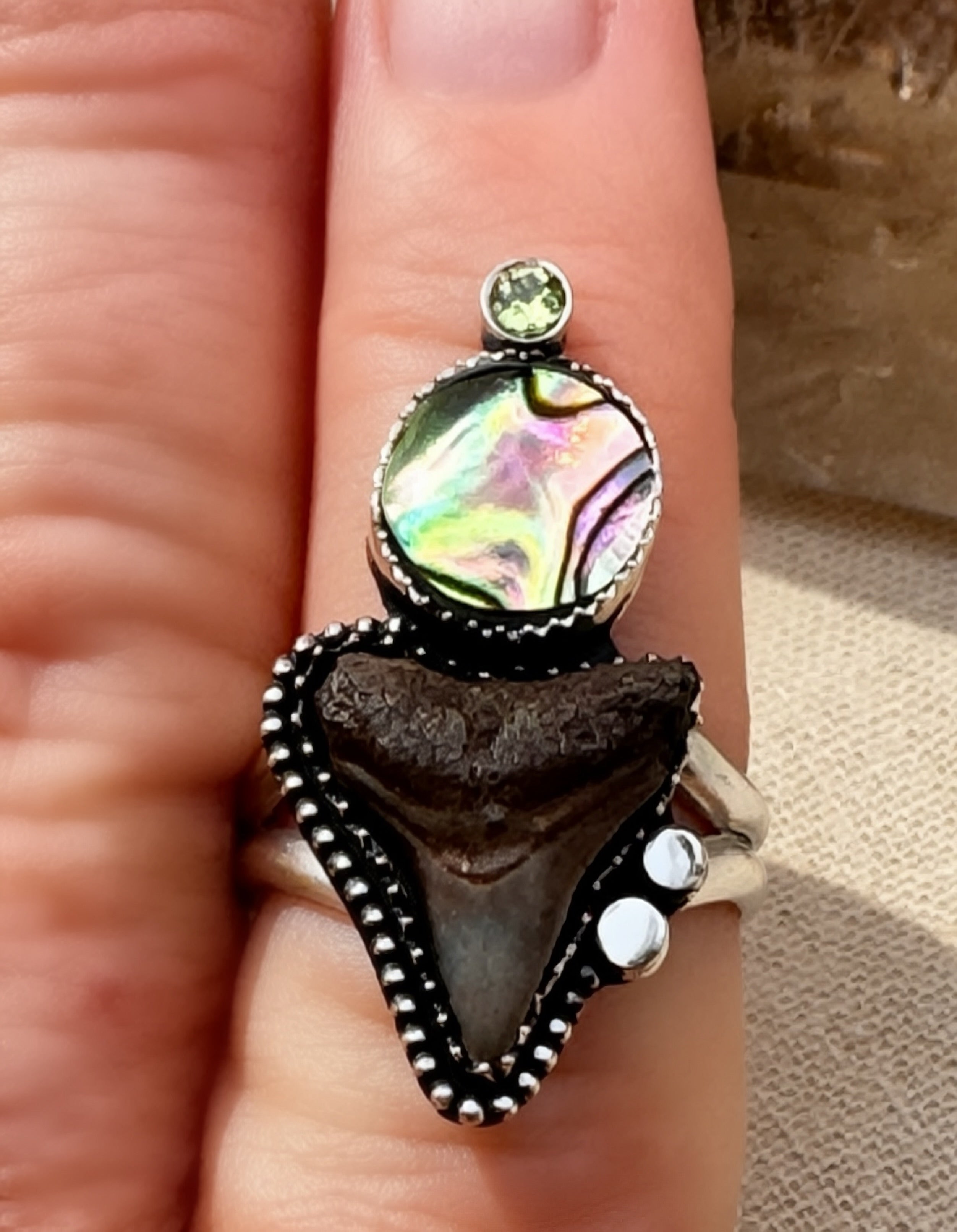 Shark tooth, abalone and peridot ring being worn.