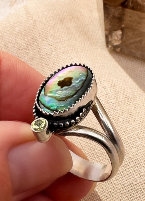 Iridescent abalone shell ring with faceted peridot and bead wire detail