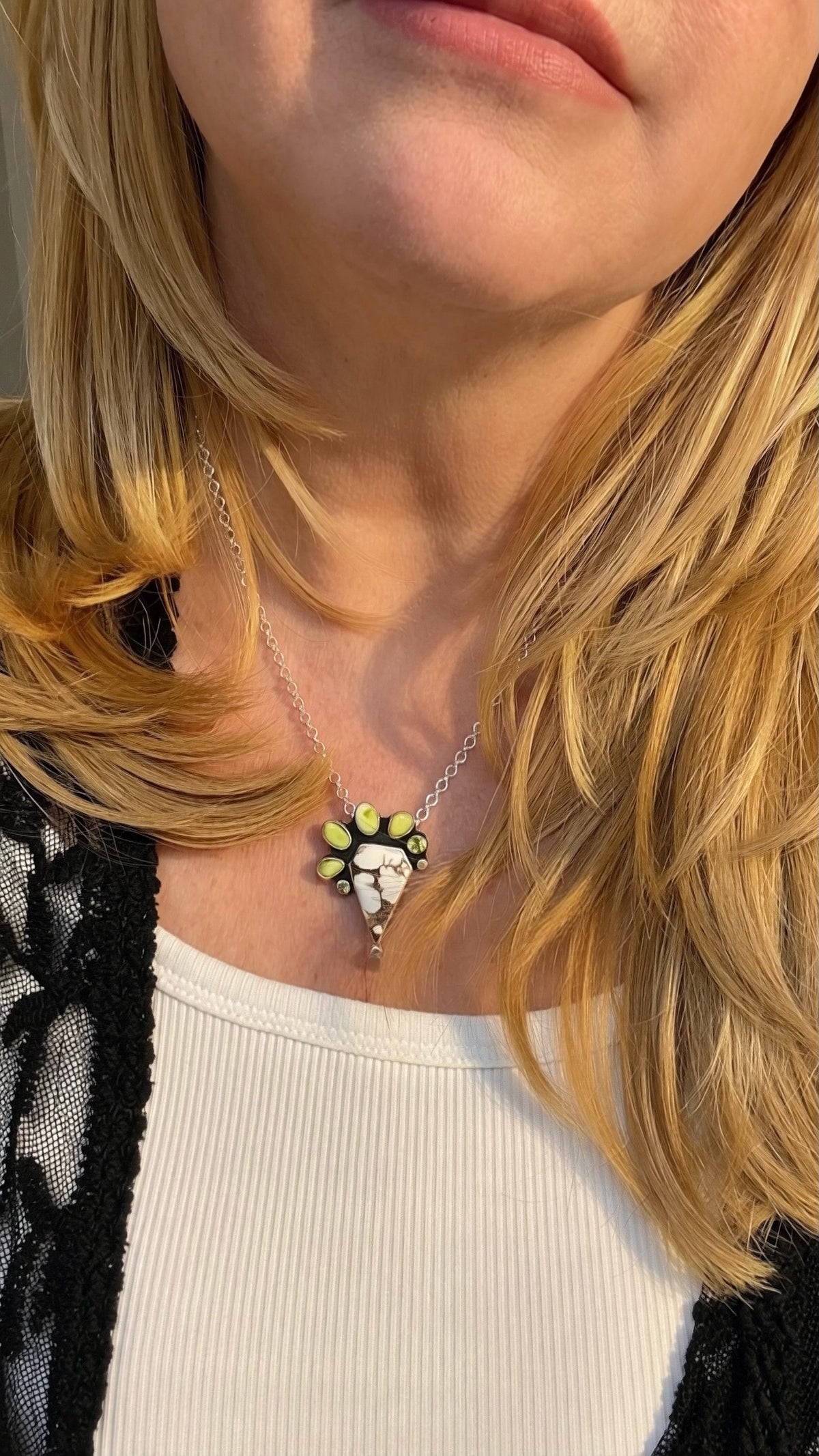 Blonde woman wearing a Wild horse and variscite pendant in sterling silver with peridot accents, handcrafted one-of-a-kind necklace. Wild horse stone is shaped like a diamond with the varisicte and palomino stones accenting the shape.