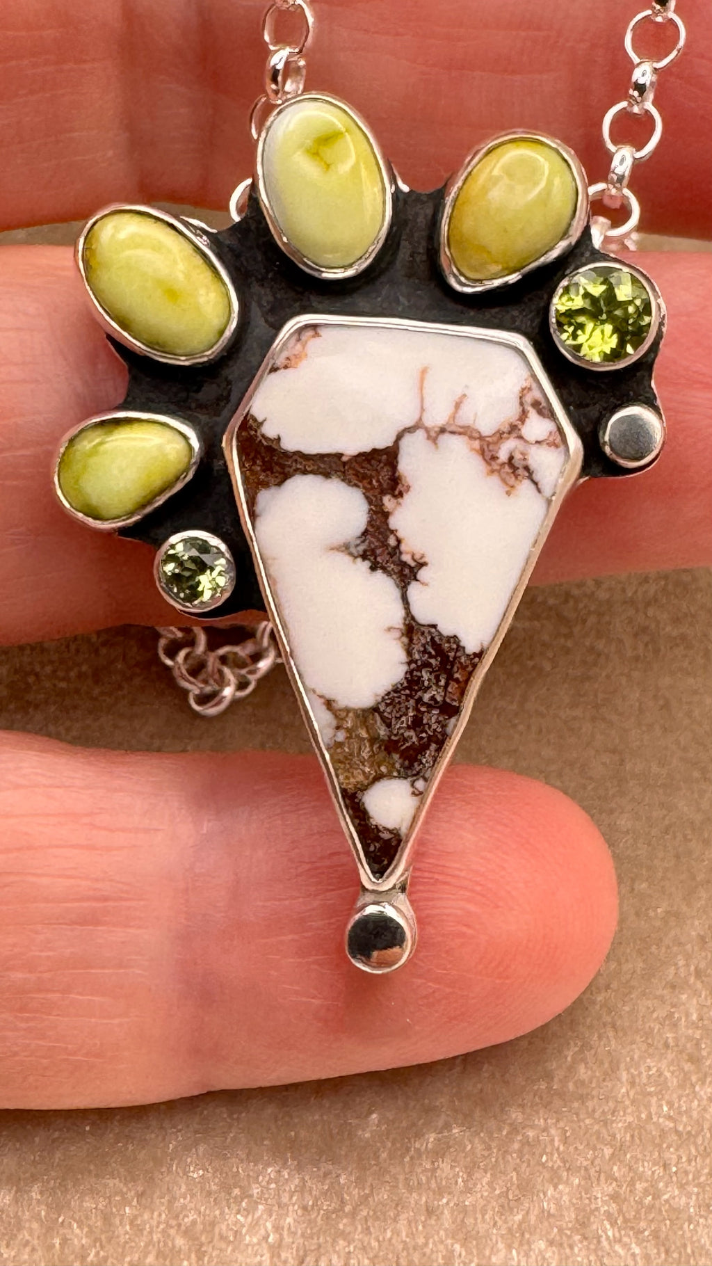 Hand holding a Wild horse and variscite pendant in sterling silver with peridot accents, handcrafted one-of-a-kind necklace.