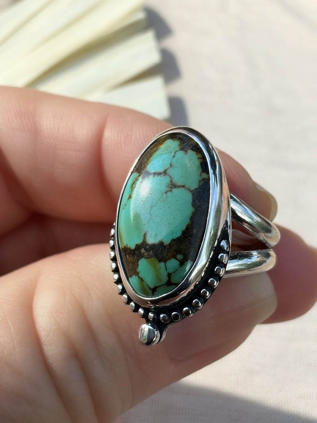 Angled view of the Pilot Mountain oval ring, showing its smooth bezel, silver bead border, and split-shank band.