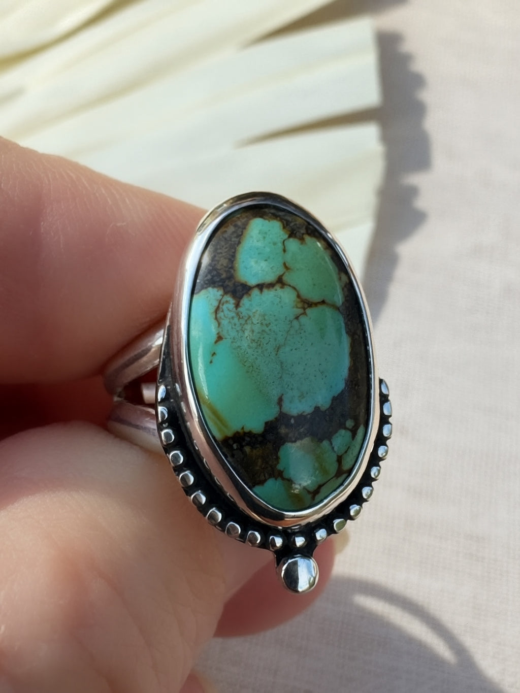 Close front view of the Pilot Mountain oval ring, showing turquoise matrix and the small silver accent below the setting.