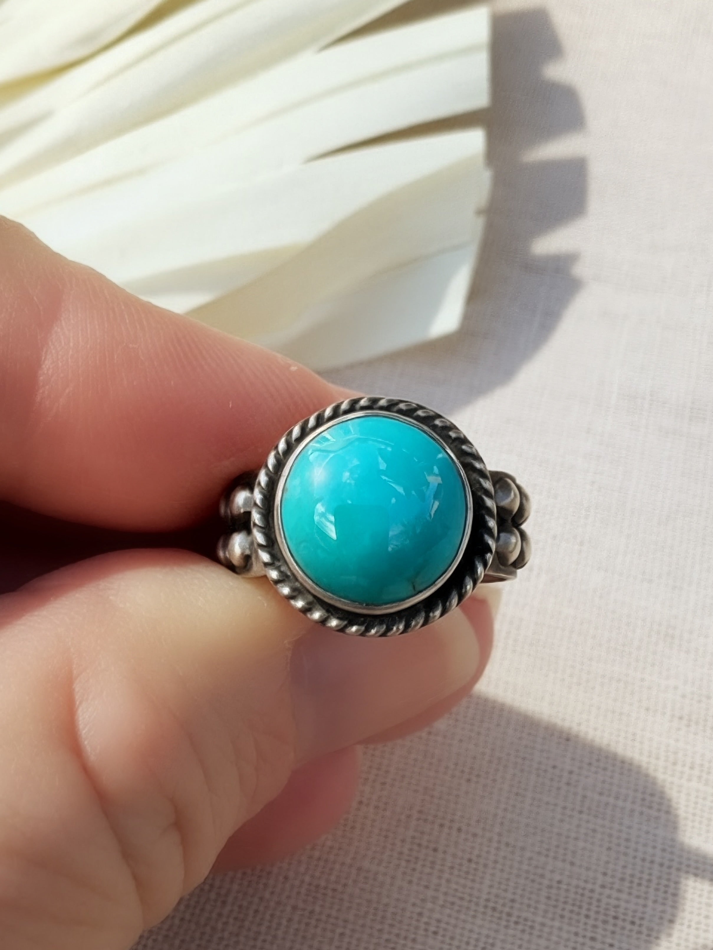 Round blue Bisbee turquoise ring in oxidized sterling silver with a twisted wire halo, handmade by Sun Salt Silver.