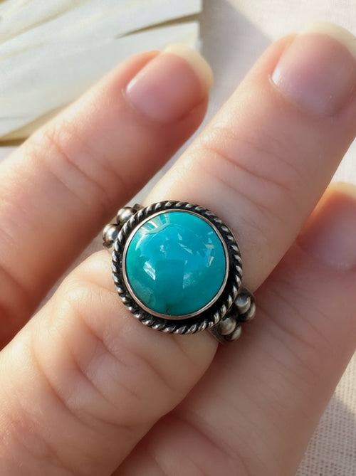 Round blue Bisbee turquoise ring in oxidized sterling silver with a twisted wire halo, handmade by Sun Salt Silver.