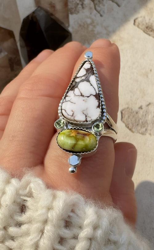 Ring with a large stone held in a hand against a neutral background