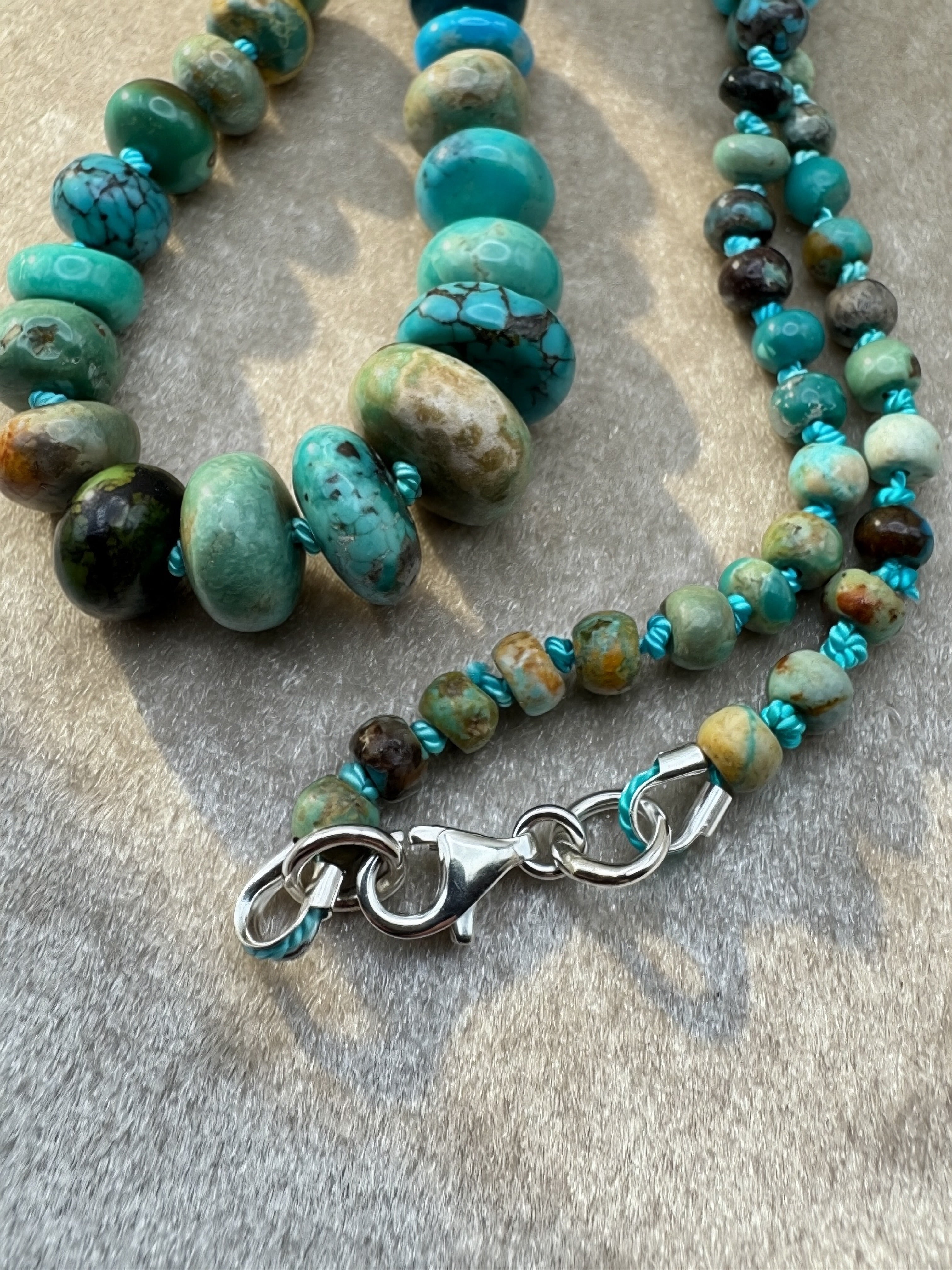 Hand knotted turquoise Beaded necklace with turquoise and brown beads on a textured surface - featuring the sterling silver clasp.