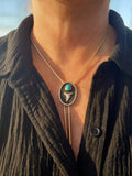 Necklace with a pendant featuring a Bisbee turquoise stone and silver shark tooth worn by a person.
