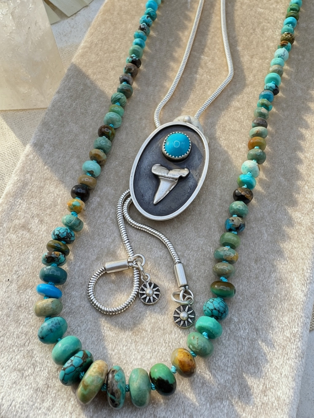 Necklace with turquoise beads and silver and turquoise bolo on a textured surface