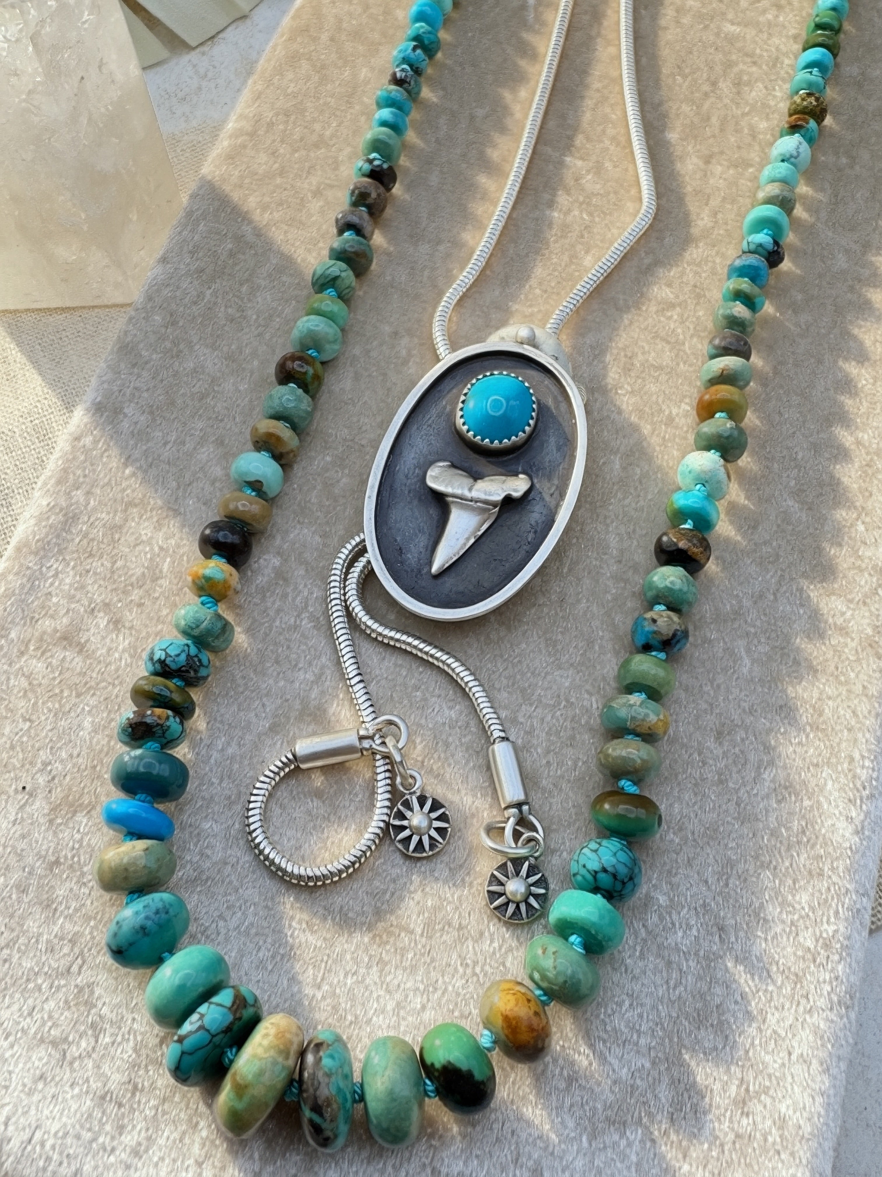 Necklace with turquoise beads and silver and turquoise bolo on a textured surface