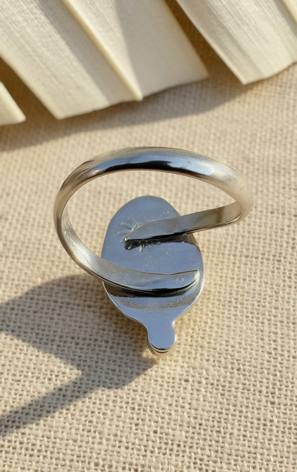 Silver ring with a unique design on a textured beige surface