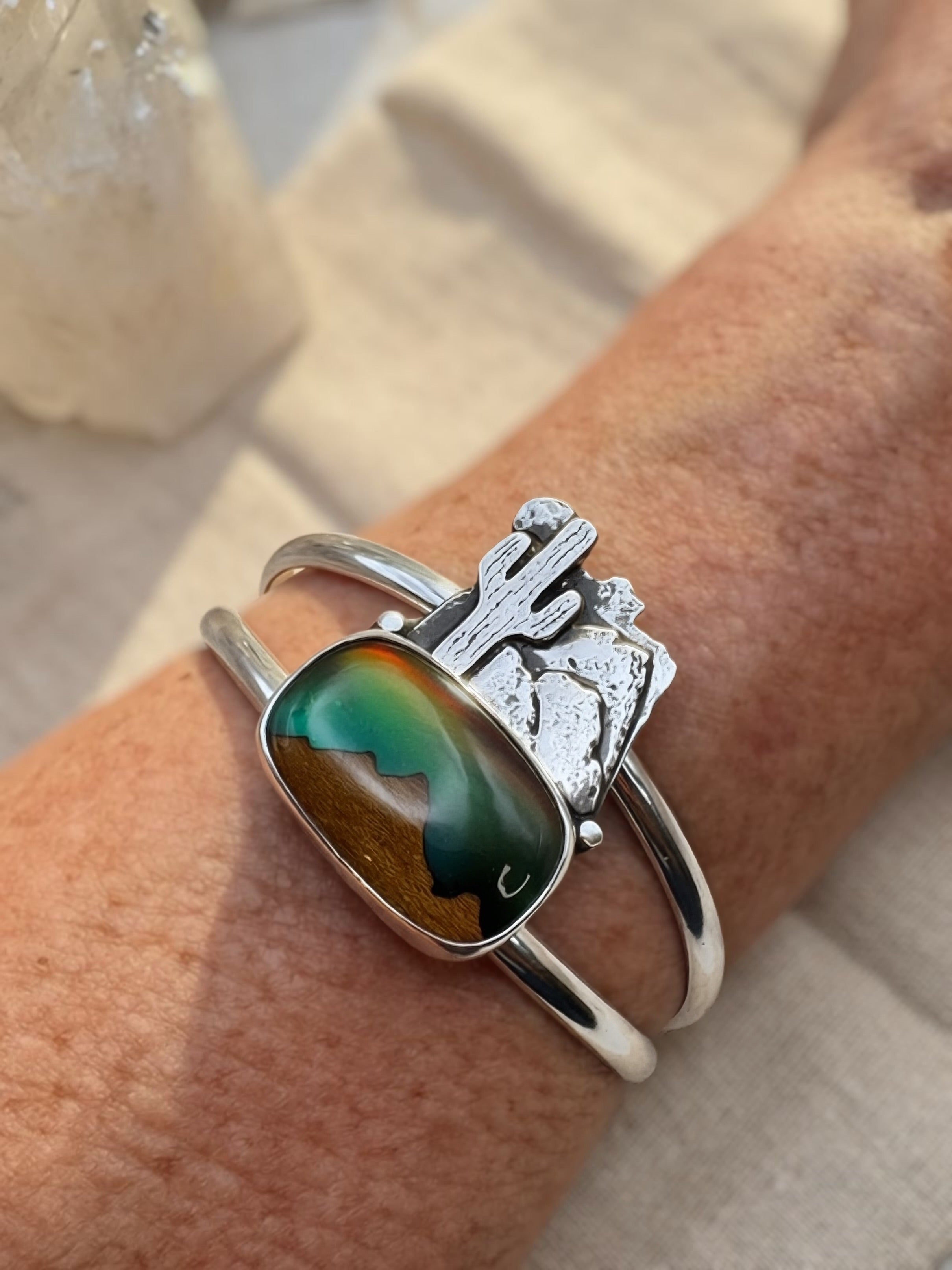 Sterling silver cuff bracelet with triplet landscape stone and hand-sawed desert scene featuring saguaro cactus and mountains, worn on wrist