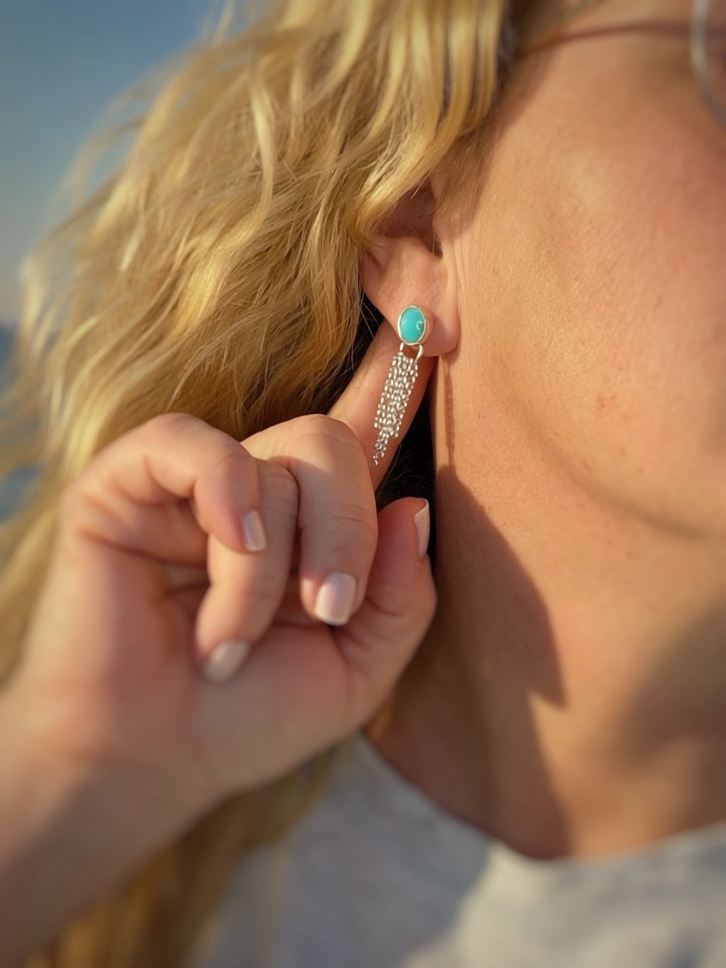 Blue turquoise earring set in silver with silver fringe being worn.