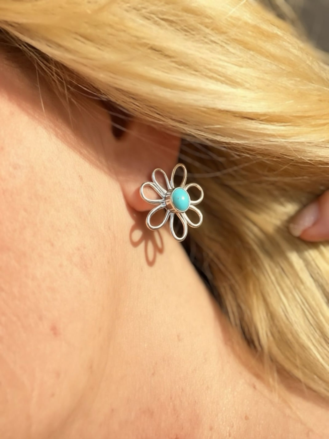 Sleeping Beauty turquoise daisy stud earring worn on ear, showing open petal sterling silver design