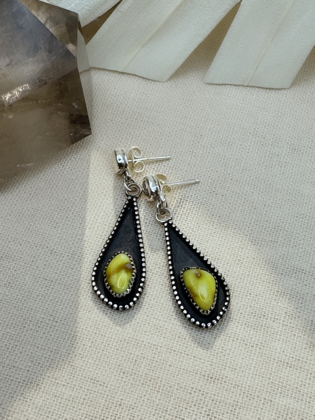 Palomino variscite earrings on cream fabric, showing chartreuse stones, dark teardrop shadowboxes, beaded borders, and post backs.