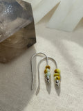 Desert Sprig Palomino variscite earrings on cream fabric, showing yellow-green beads, silver bead accents, and long curved ear wires.