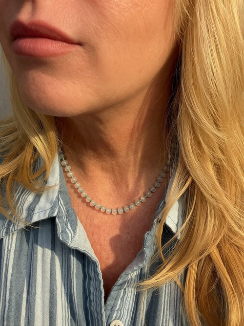 Hand knotted candy jade necklace worn at collarbone length on woman in striped shirt