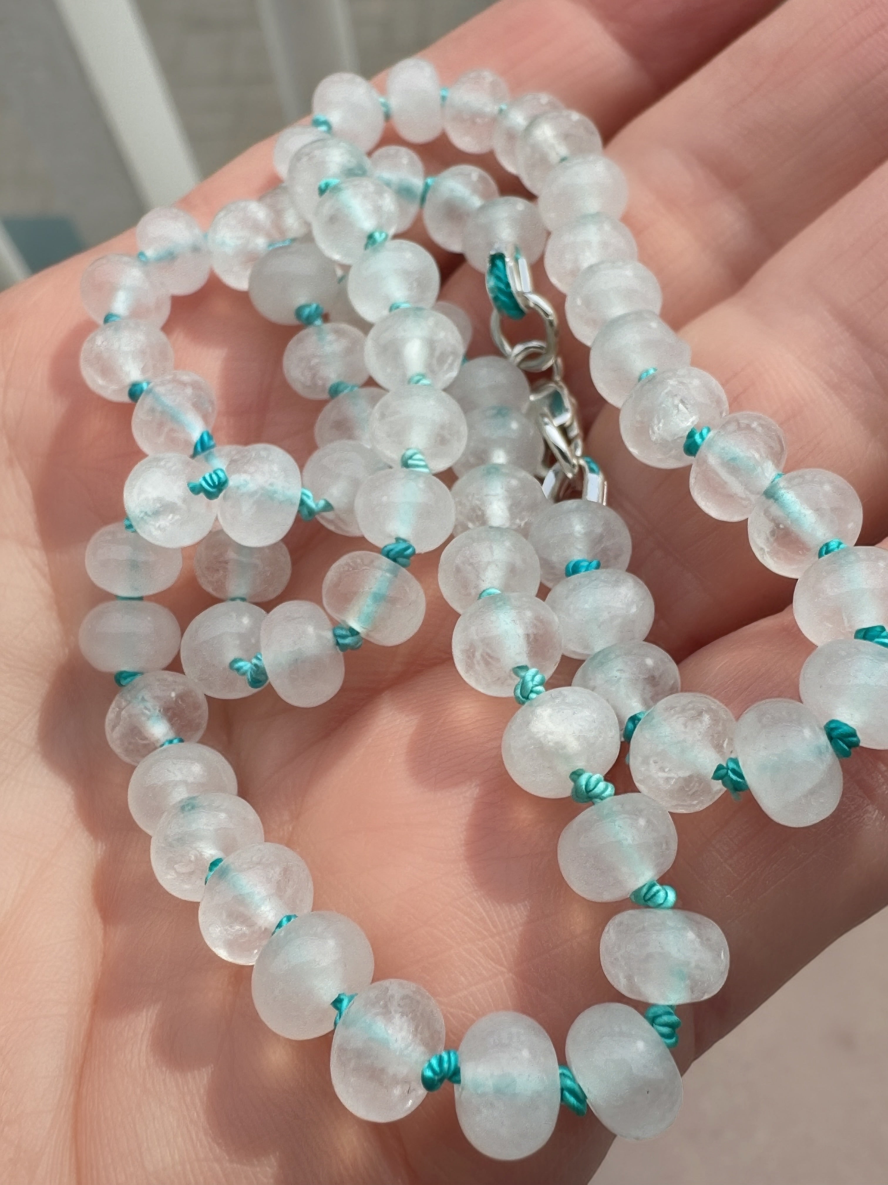 Close-up of candy jade rondelle beads hand knotted on turquoise silk thread
