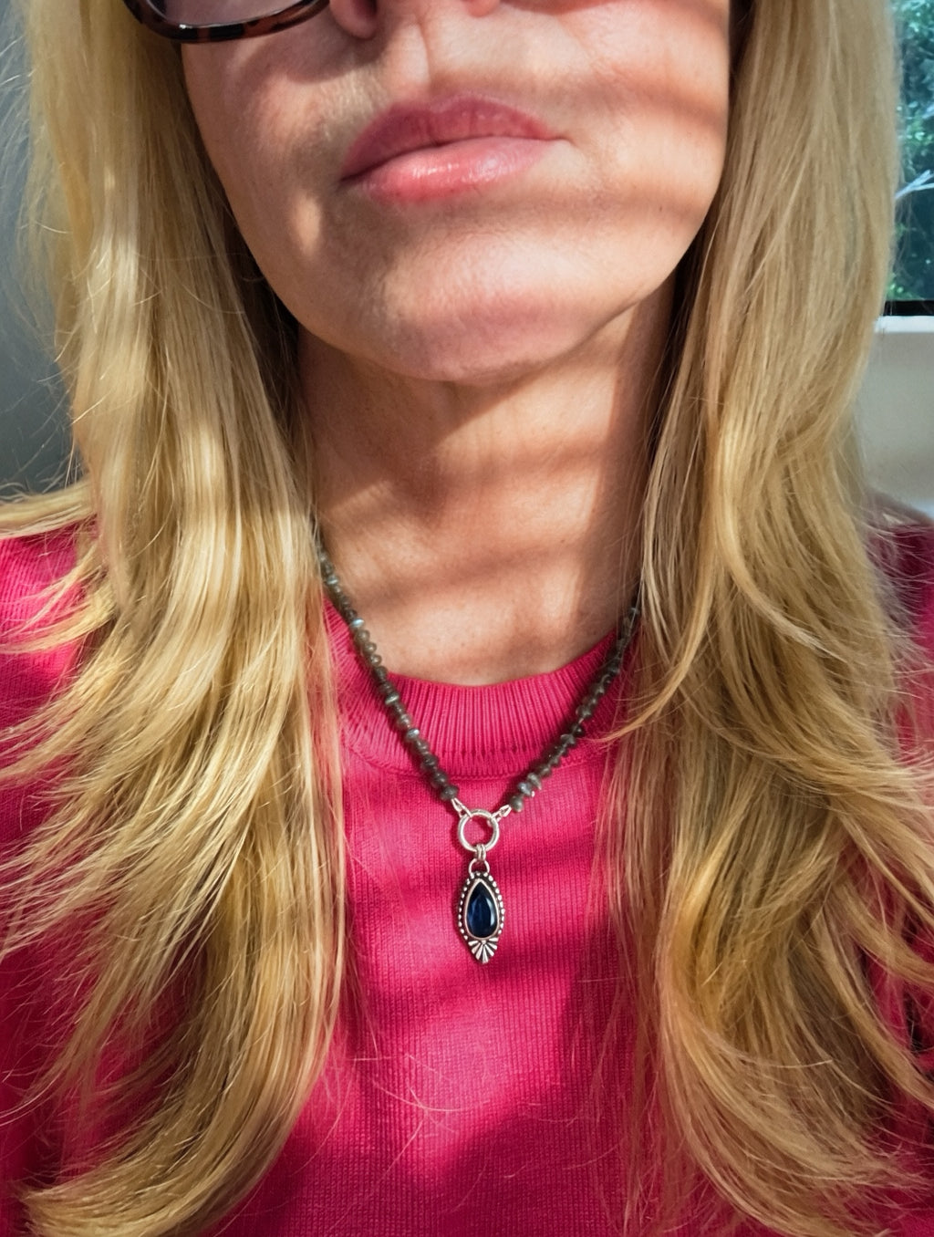 Blue Hour Bloom teal kyanite and labradorite necklace worn with a bright pink top to show its 16-inch length and pendant scale.