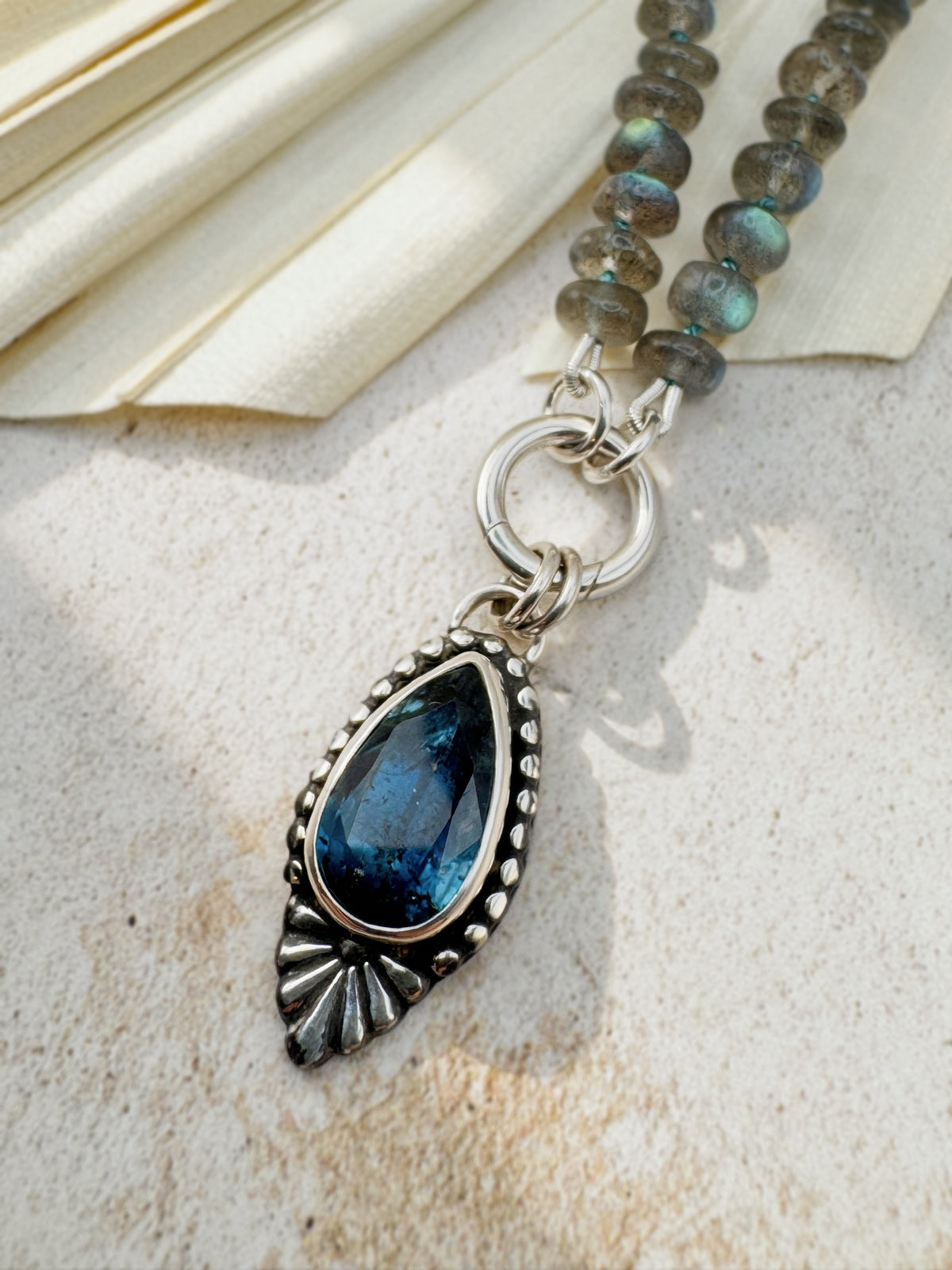 Full Blue Hour Bloom necklace with hand-knotted labradorite beads, sterling silver charm keeper and faceted teal kyanite floral pendant.