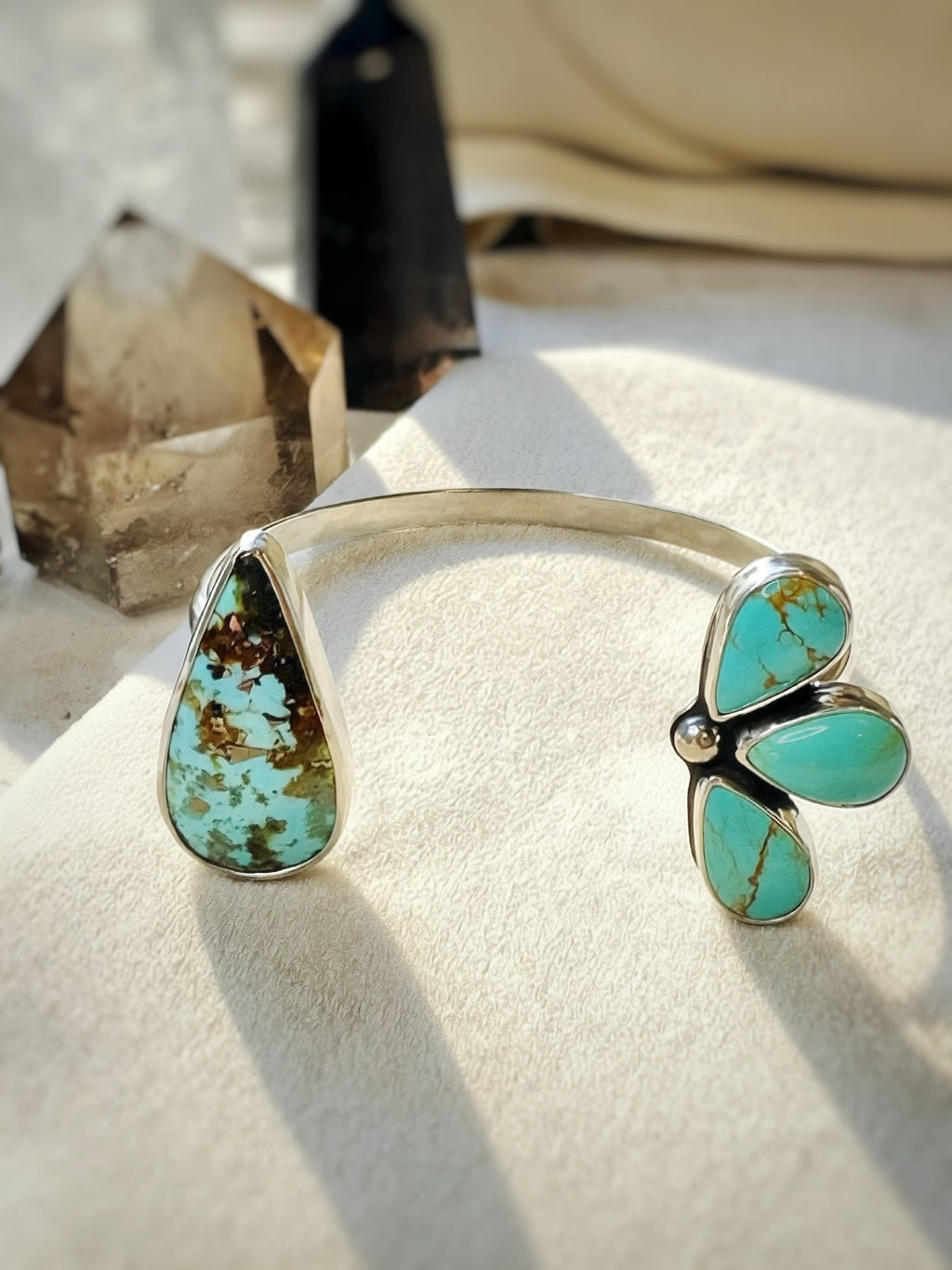 Turquoise butterfly-shaped bracelet on a textured surface with crystals in the background