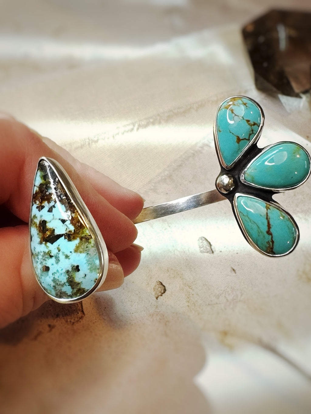 Turquoise multi-stone cuff held by a hand on a light background