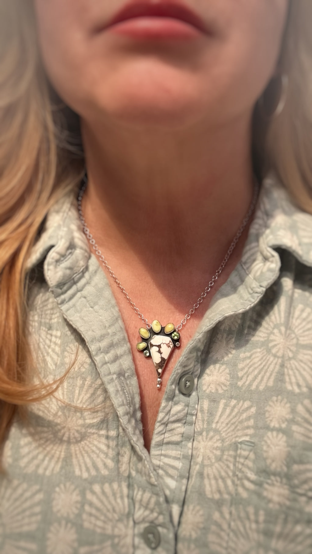 Woman wearing wild horse stone pendant necklace on 18-inch sterling silver chain In noon day light.