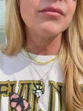 Close-up of a person wearing a white shirt with text and graphics, including a necklace.