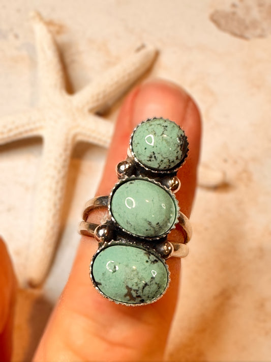 3 Turquoise stone statement ring on a hand with sand and starfish in the background
