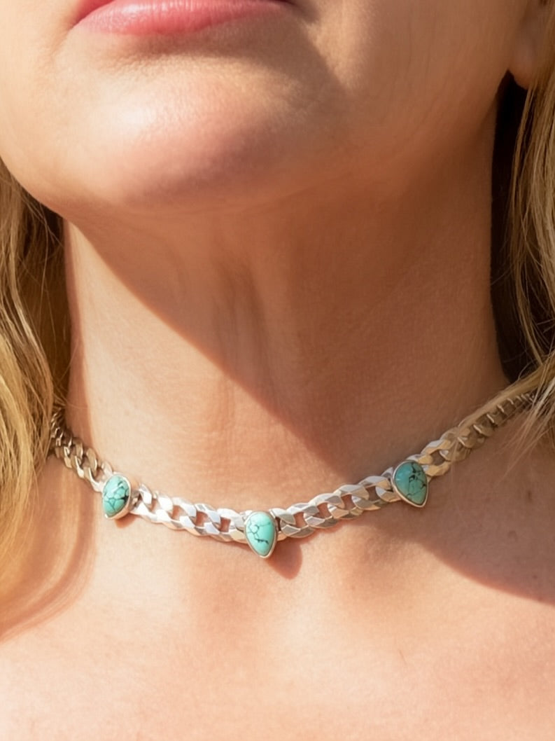 Blue Reign turquoise curb chain necklace worn close to the neck in sunlight, showing the three stone settings.