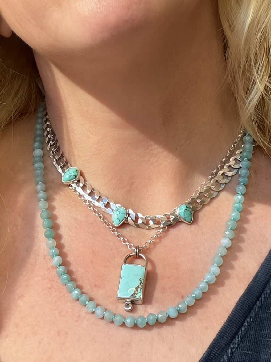 Blue Reign curb chain necklace layered with a separate rectangular turquoise pendant and pale blue beaded strand.