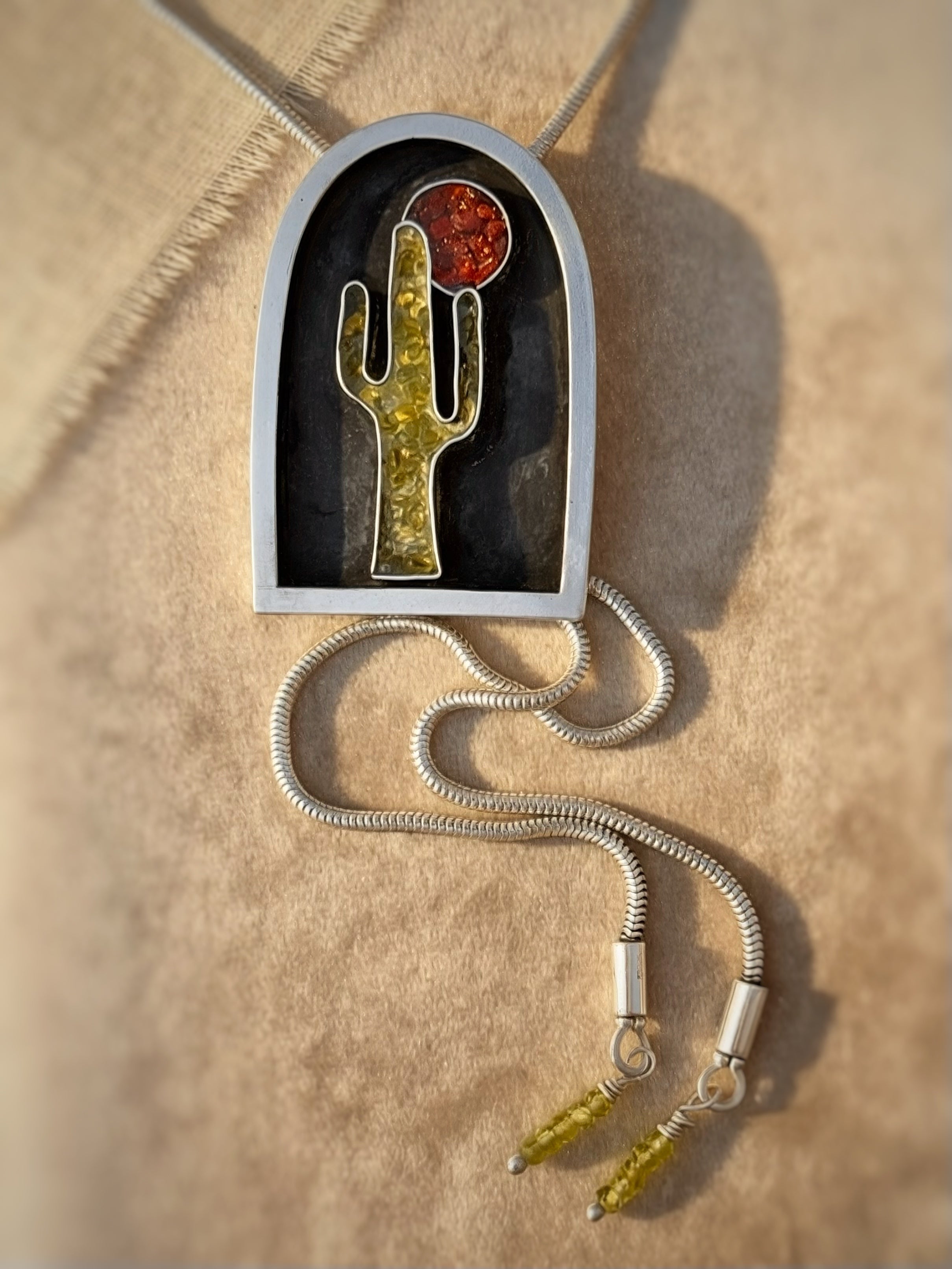 Necklace with a pendant featuring a cactus design on a beige background