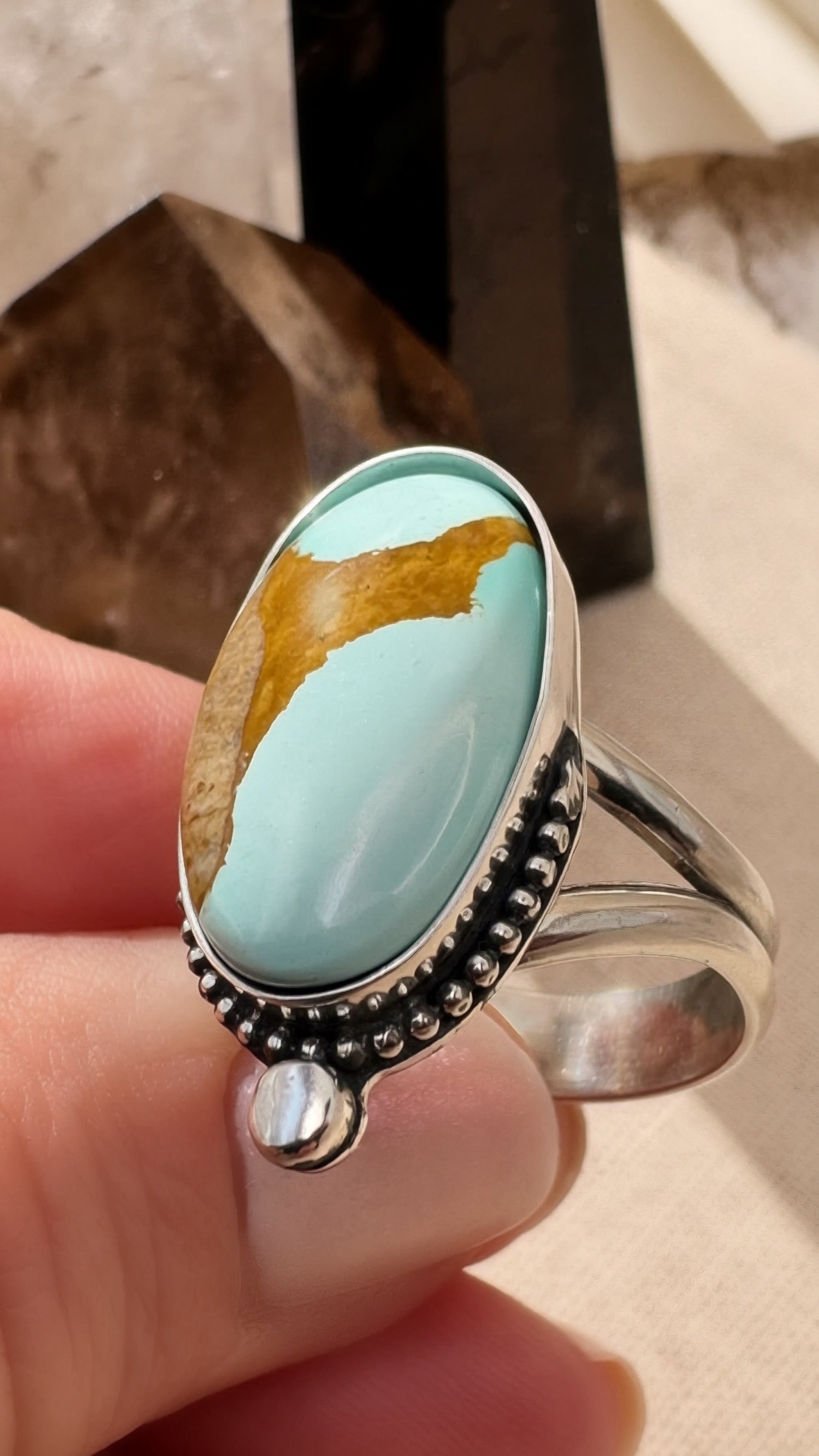 Turquoise ring with silver band held in a hand