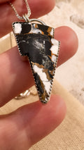 Lightning bolt-shaped pendant held in a hand with a blurred background
