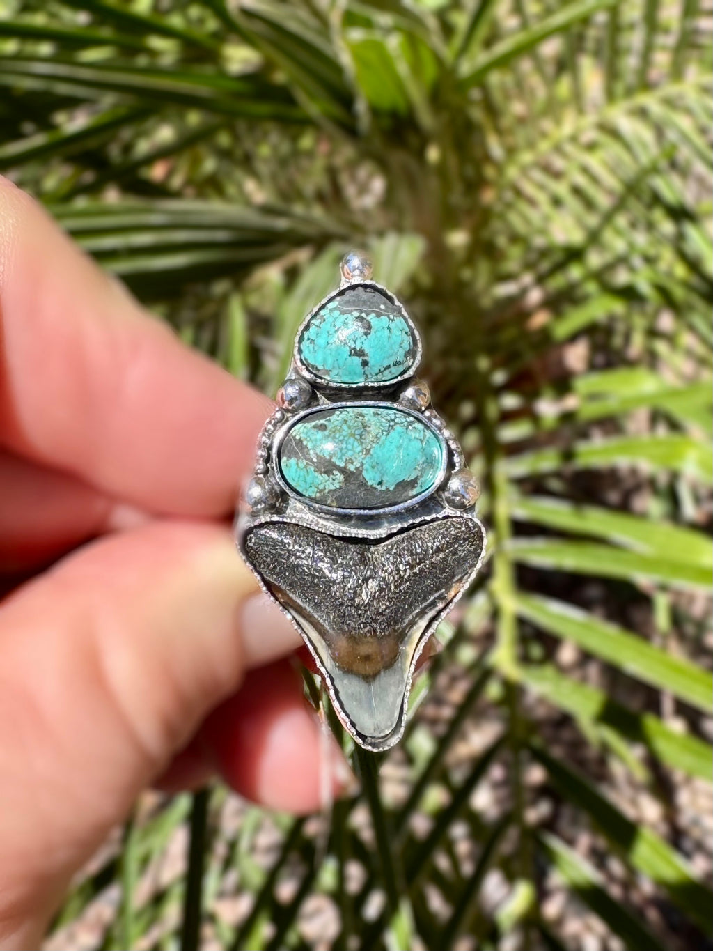 Turquoise ring held by a hand with a natural background