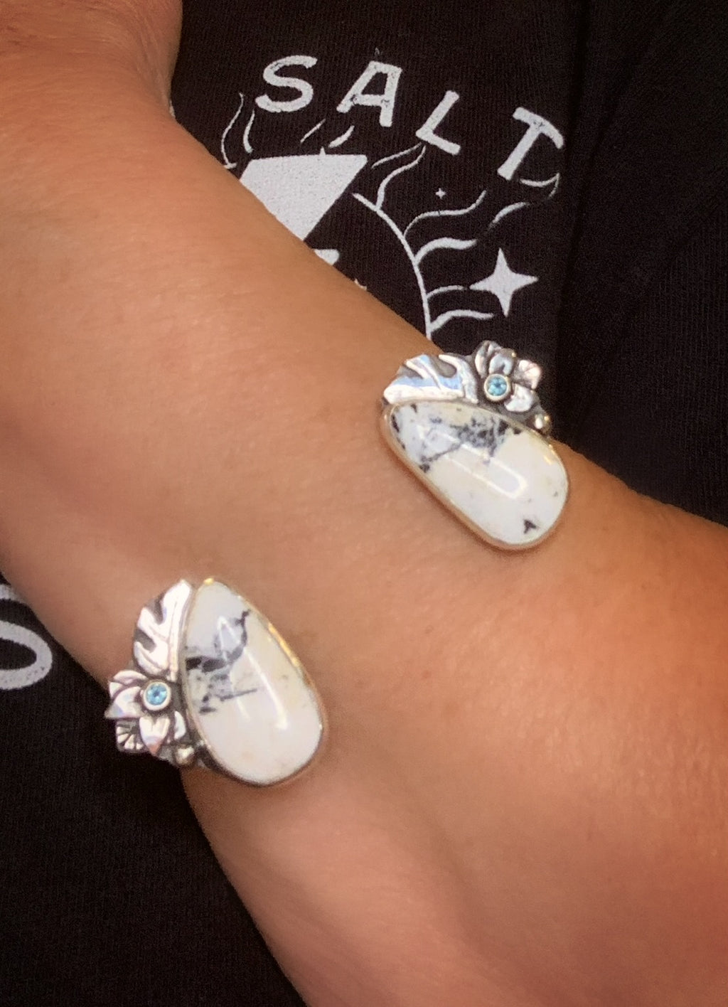 Close-up of a wrist wearing a silver, white buffalo, Montana sapphire and monstera leaf cuff. 