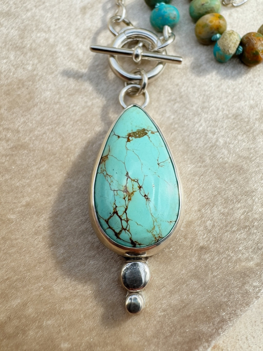 Close up of a Glacier blue turquoise teardrop pendant in sterling silver bezel setting with natural turquoise rondelle bead strand and charm keeper toggle clasp, Sun Salt Silver Caye Collection