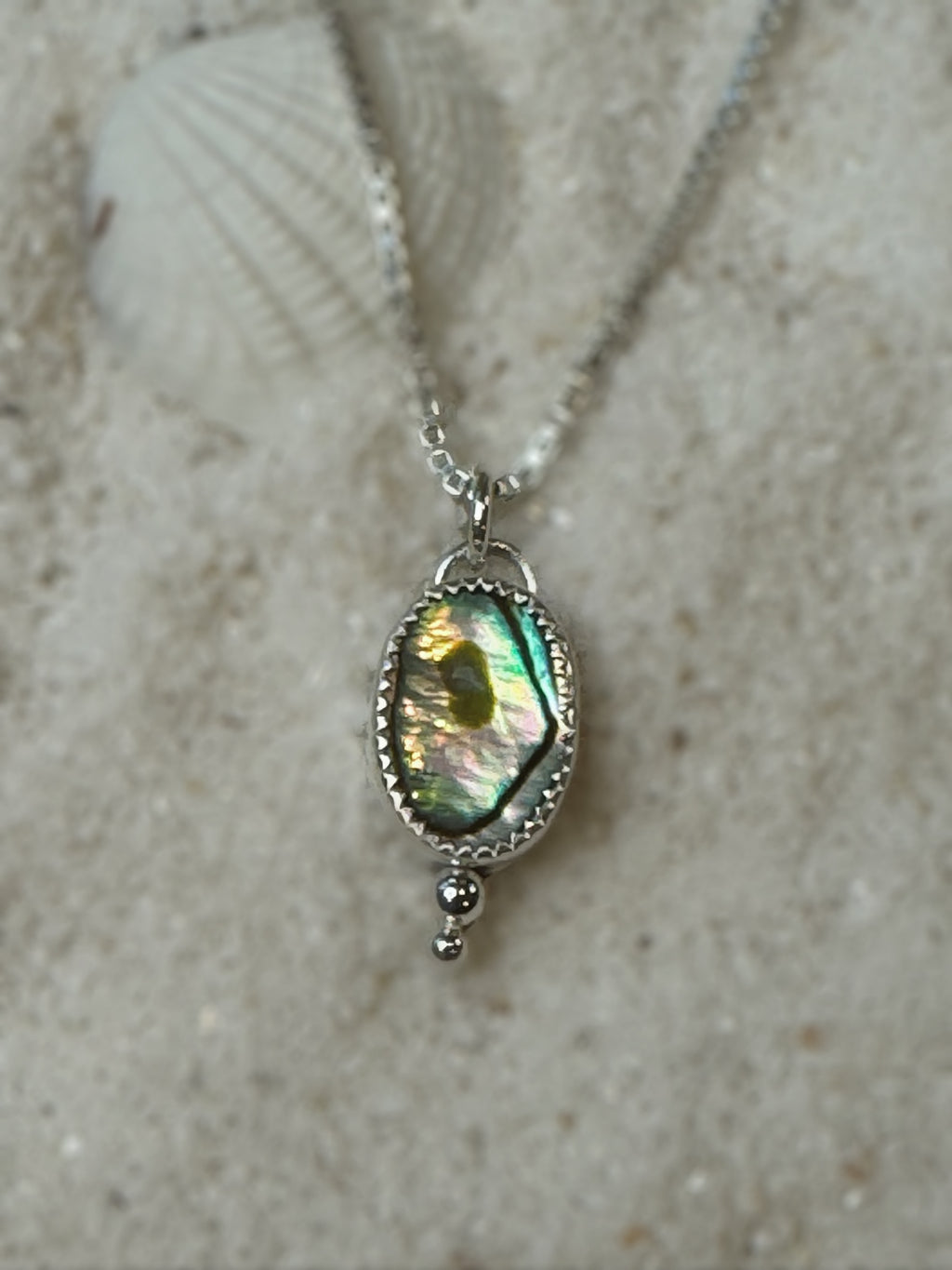 Abalone shell Necklace with a pendant on a textured beige surface