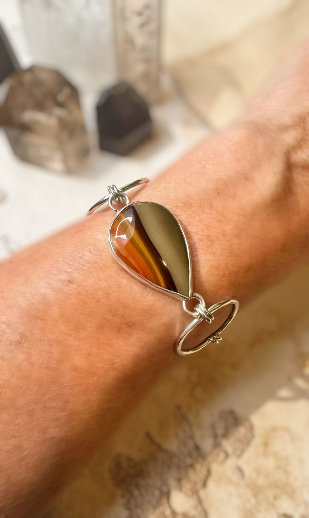 Bracelet with a tear drop shaped Jasper-on a wrist against a blurred natural background