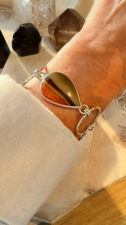 Close up of a person wearing a silver and desert jasper bracelet.